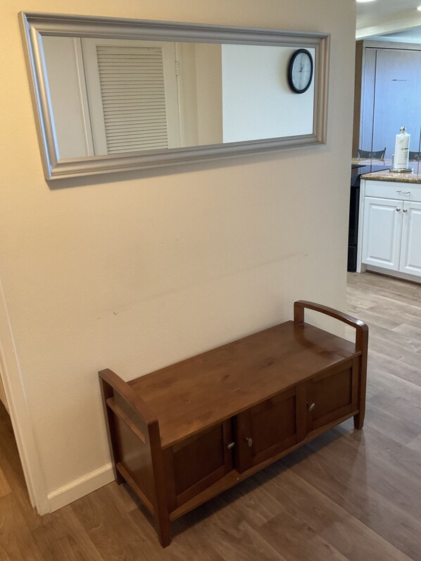 A wooden bench with a mirror above it, a clock on the wall, and a kitchen area in the background. - floor to ceiling windows,180 degree view of ocean, 11th floor (San Diego)