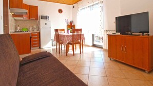 A compact living space with a kitchenette, a dining area, and a TV.