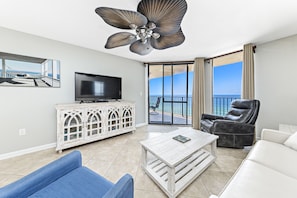 Relax in this stylish living room with a large flat-screen TV, comfortable seating, and a balcony offering ocean views.