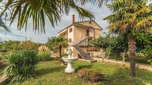A house with a garden, a fountain, and a staircase leading to the entrance. - Holiday apartment with terrace and whirlpool in the garden (Maružini)