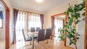 A conference room with a glass table, four chairs, and a potted plant. - Holiday apartment with terrace and whirlpool in the garden (Maružini)