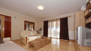 A modern living room with a sofa, coffee table, and TV. - Holiday apartment with terrace and whirlpool in the garden (Maružini)