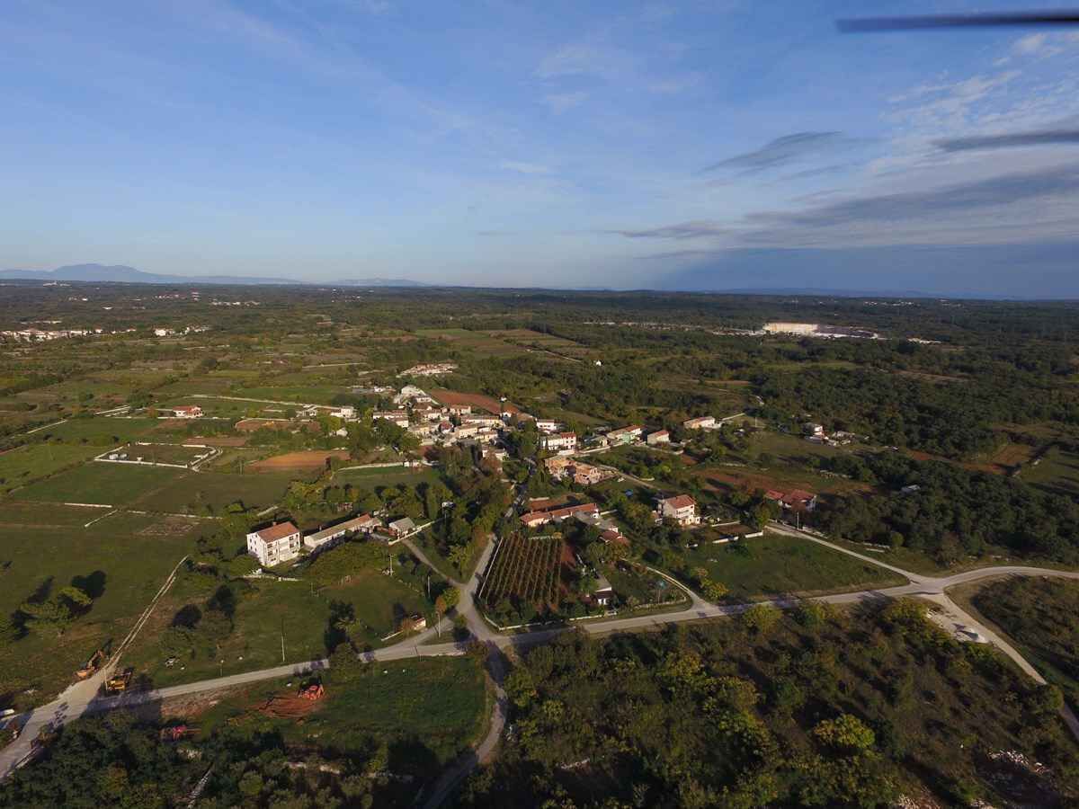 Une vue aérienne d’une petite ville avec des immeubles résidentiels, des routes et des champs verdoyants.