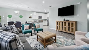 A modern living room with a sofa, chairs, a coffee table, and a TV. - Comforts of home and just a 5 min walk to the beach! Plus private pool (Panama City Beach)