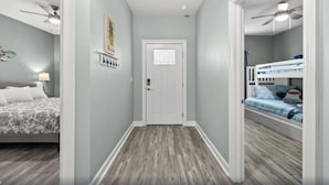 A hallway with a wooden floor, a white door, and a bunk bed with blue bedding. - Comforts of home and just a 5 min walk to the beach! Plus private pool (Panama City Beach)