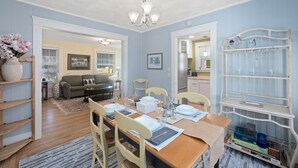A dining area with a wooden table set for four, chairs, and a white shelf with containers.