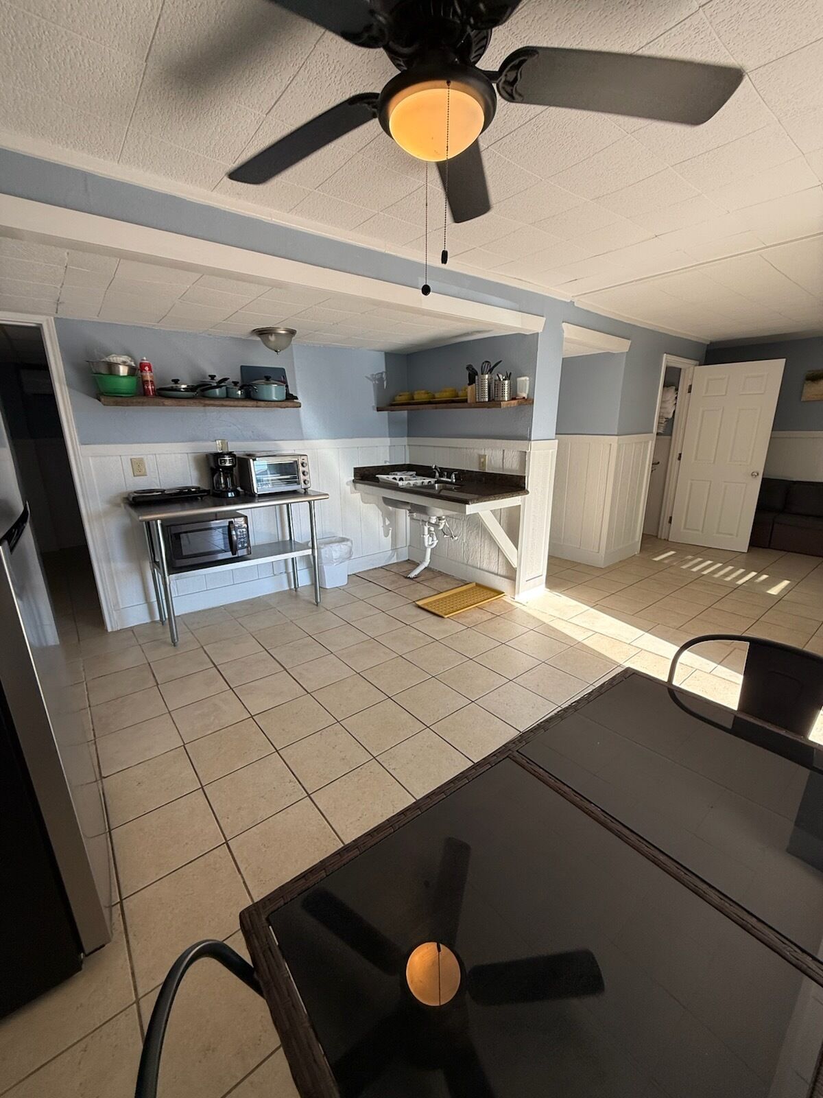 A compact kitchen with a ceiling fan, a dining table, and a small seating area.