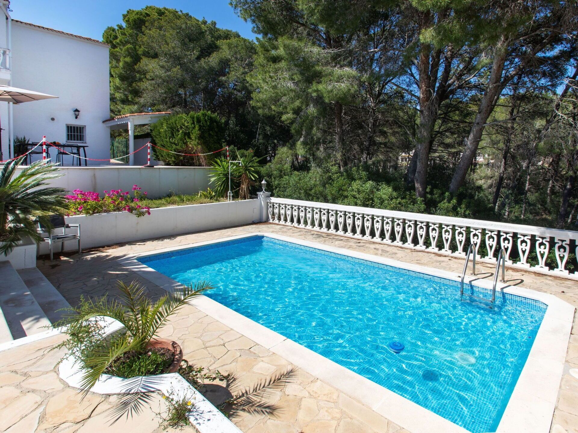 A rectangular swimming pool with a tiled edge, surrounded by a white decorative fence.