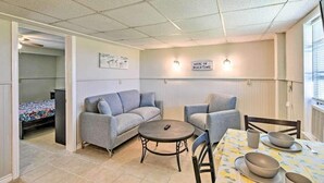 A compact room with a sofa, a small round table, and a dining table with bowls and cups. - The Mark at Surfside, Apt. 2 (Surfside Beach)
