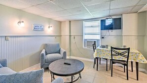 A room with a round table, two armchairs, a TV mounted on the wall, and a sign that reads "WERE ON BEACH TIME." - The Mark at Surfside, Apt. 2 (Surfside Beach)
