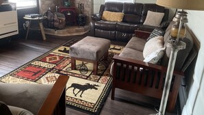 A cozy living room with a leather sofa, a patterned rug, and a fireplace.
