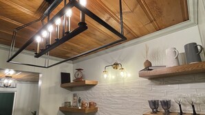 A modern kitchen with a wooden ceiling, a double sink, and built-in shelves with various kitchen items.