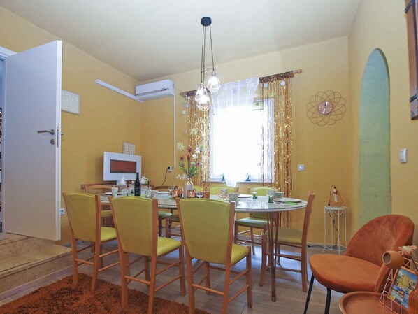 A dining area with a round table, yellow chairs, and a modern pendant light.