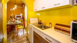Una cocina con armarios blancos, un lavamanos de acero inoxidable y un microondas.