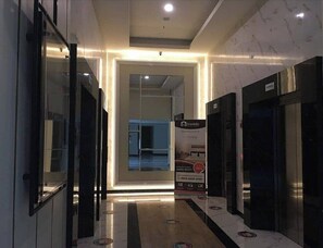 Experience the sleek lobby with a central glass partition, polished floor, and marble-like patterned walls.