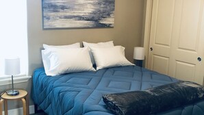 A bedroom with a bed, a nightstand, a lamp, a window, and a door. - Private, comfy and cozy apartment in family neighborhood (Oregon City)
