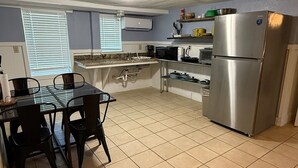 Una cocina con una mesa de comedor, sillas, un refrigerador y un microondas.