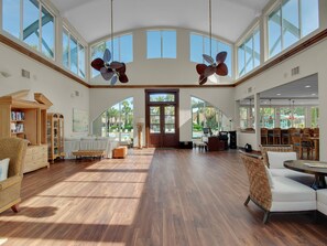Relax in this spacious room with high ceilings, large windows, and comfortable seating options.