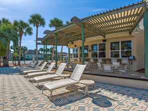 Relax by the pool surrounded by palm trees and a shaded pergola.