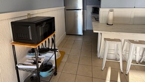 A compact kitchen with a refrigerator, microwave, and a small dining area with stools.