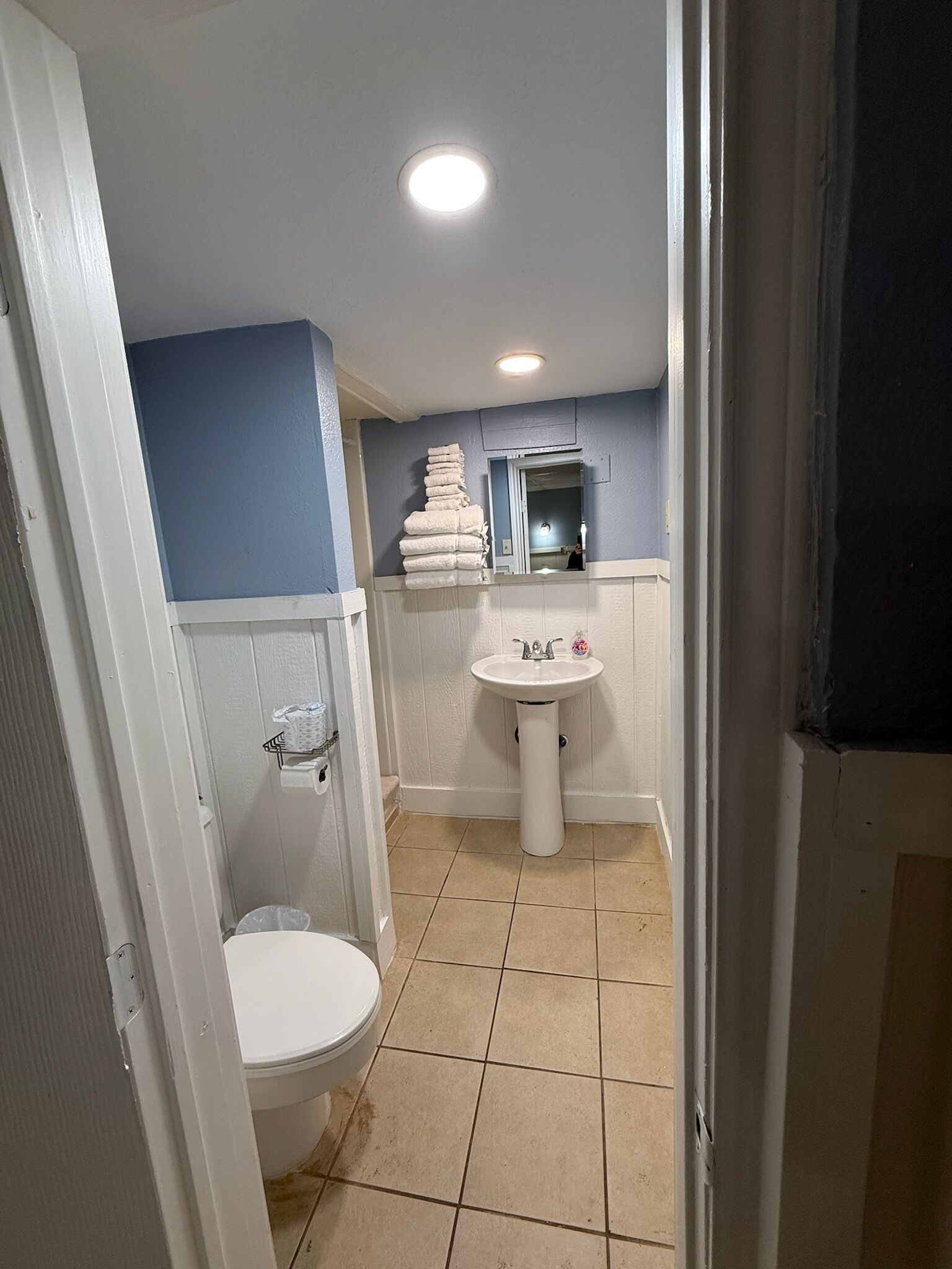 Ein Badezimmer mit Toilette, Waschbecken und einem Stapel Handtücher.