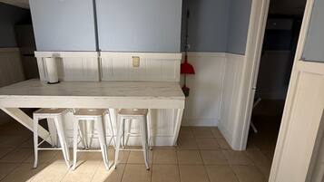 A kitchen with a white table and stools, a red broom, and a white door.