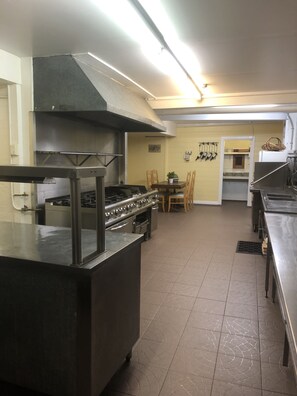 Functional kitchen with a dining area, equipped with a stove, range hood, and wooden table and chairs.
