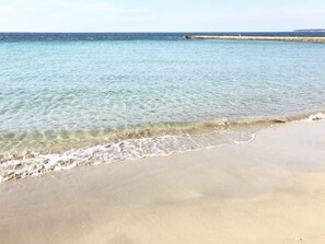 Une plage avec une eau claire et peu profonde et un rivage sablonneux.