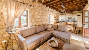 A cozy living room with a beige sectional sofa, a wooden coffee table, and a stone wall.