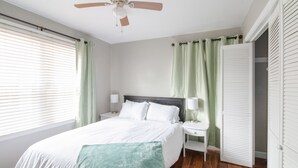 Une chambre à coucher comprenant un lit, des tables de chevet, un ventilateur de plafond et un placard.