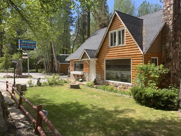 A log cabin-style building with a stone foundation, a large window, and a stone wall. - Grey Squirrel Resort (Big Bear Lake)