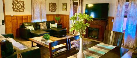 Una sala de estar con sofá, mesa de centro, sillas, chimenea y televisor.