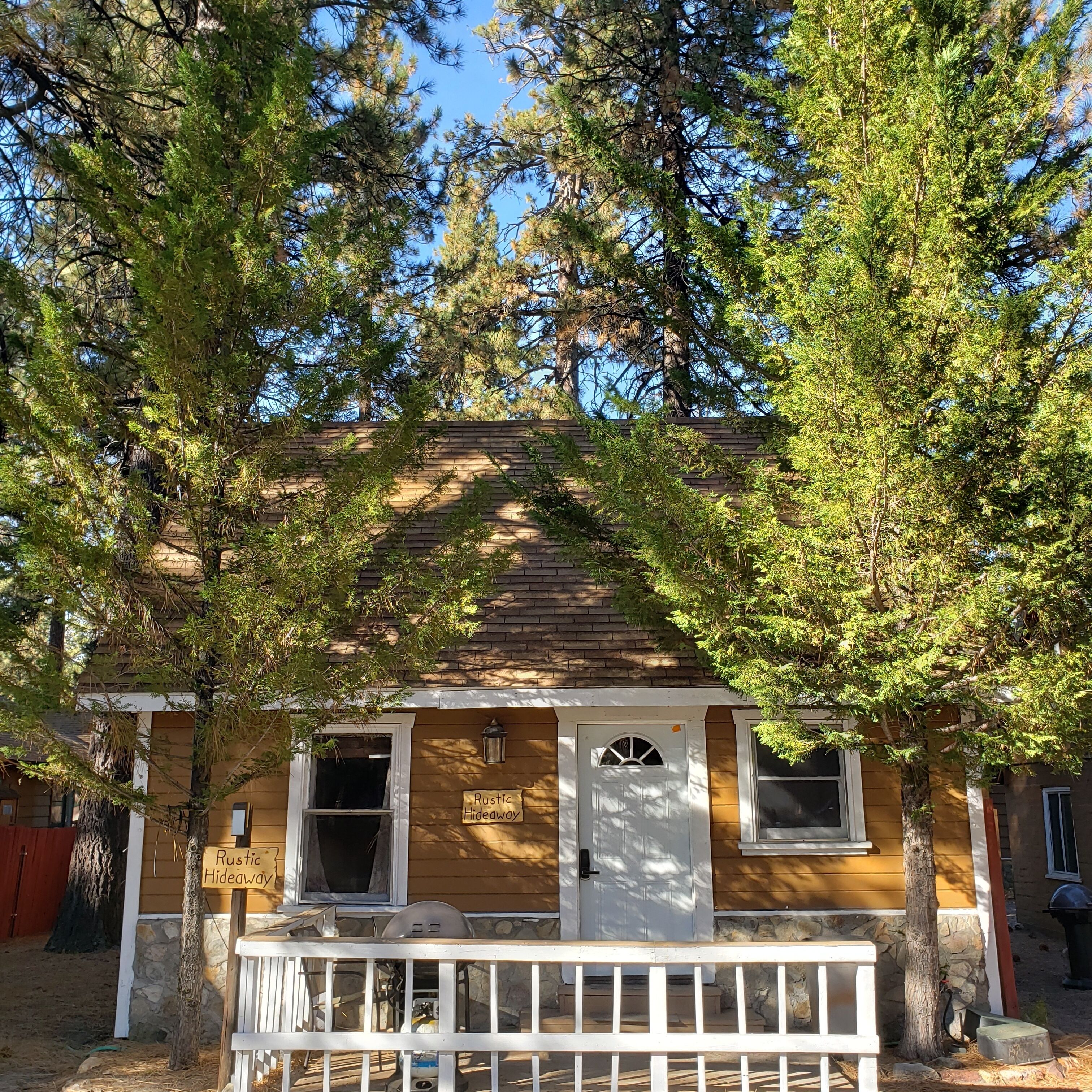 A rustic hideaway with a wooden exterior, a front porch, and a sign indicating its name.