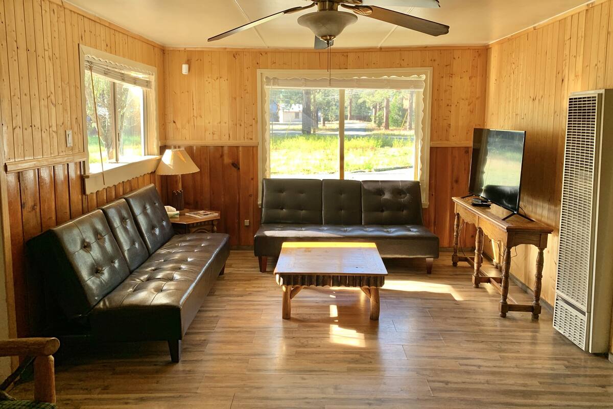 A cozy room with a ceiling fan, a sofa, a table, and a TV.