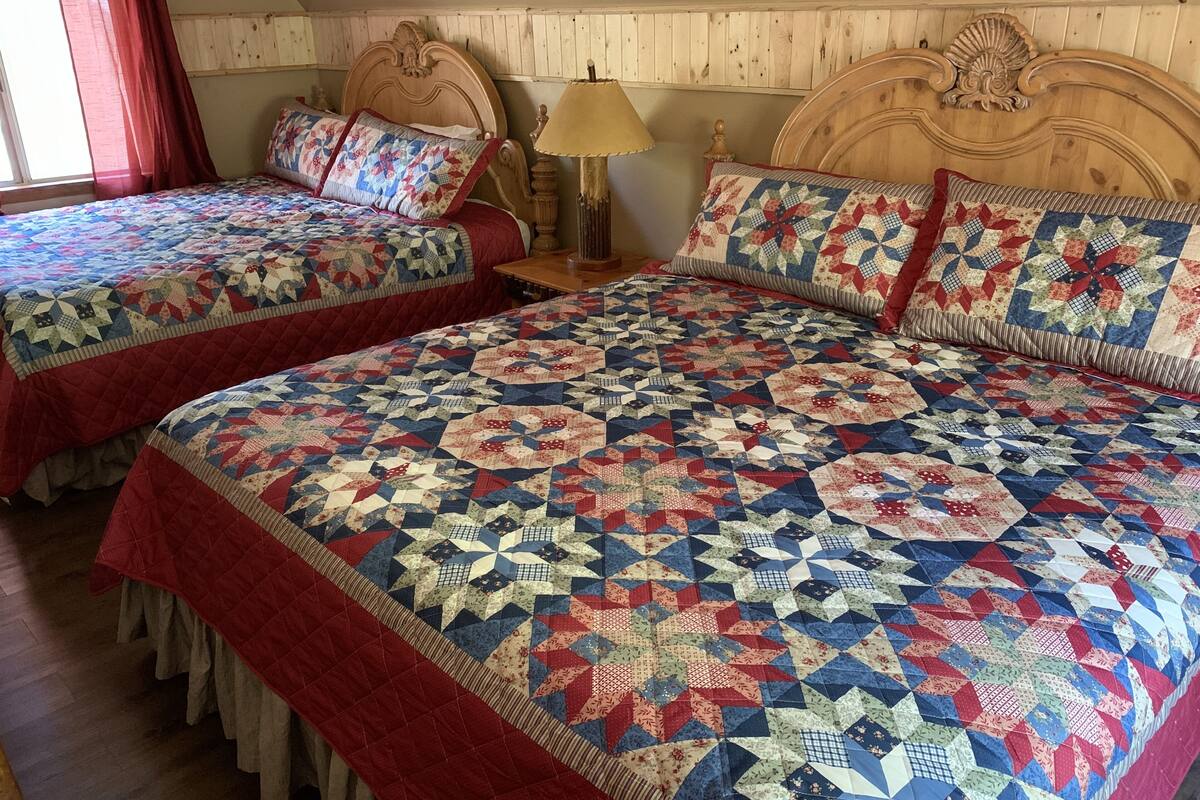 A bedroom with two beds, each with a quilted bedspread and matching pillows.