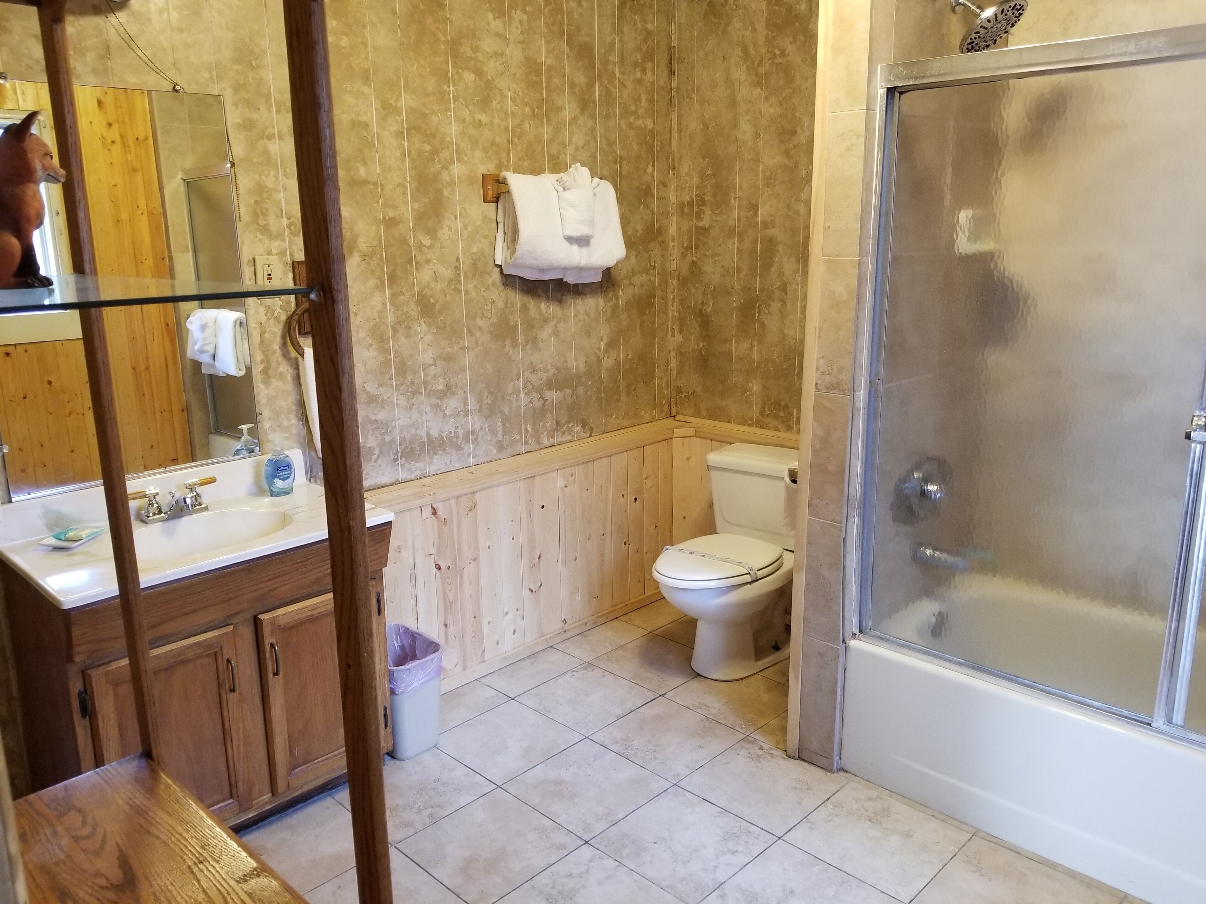 A bathroom with a wooden vanity, a glass shower enclosure, and a toilet.