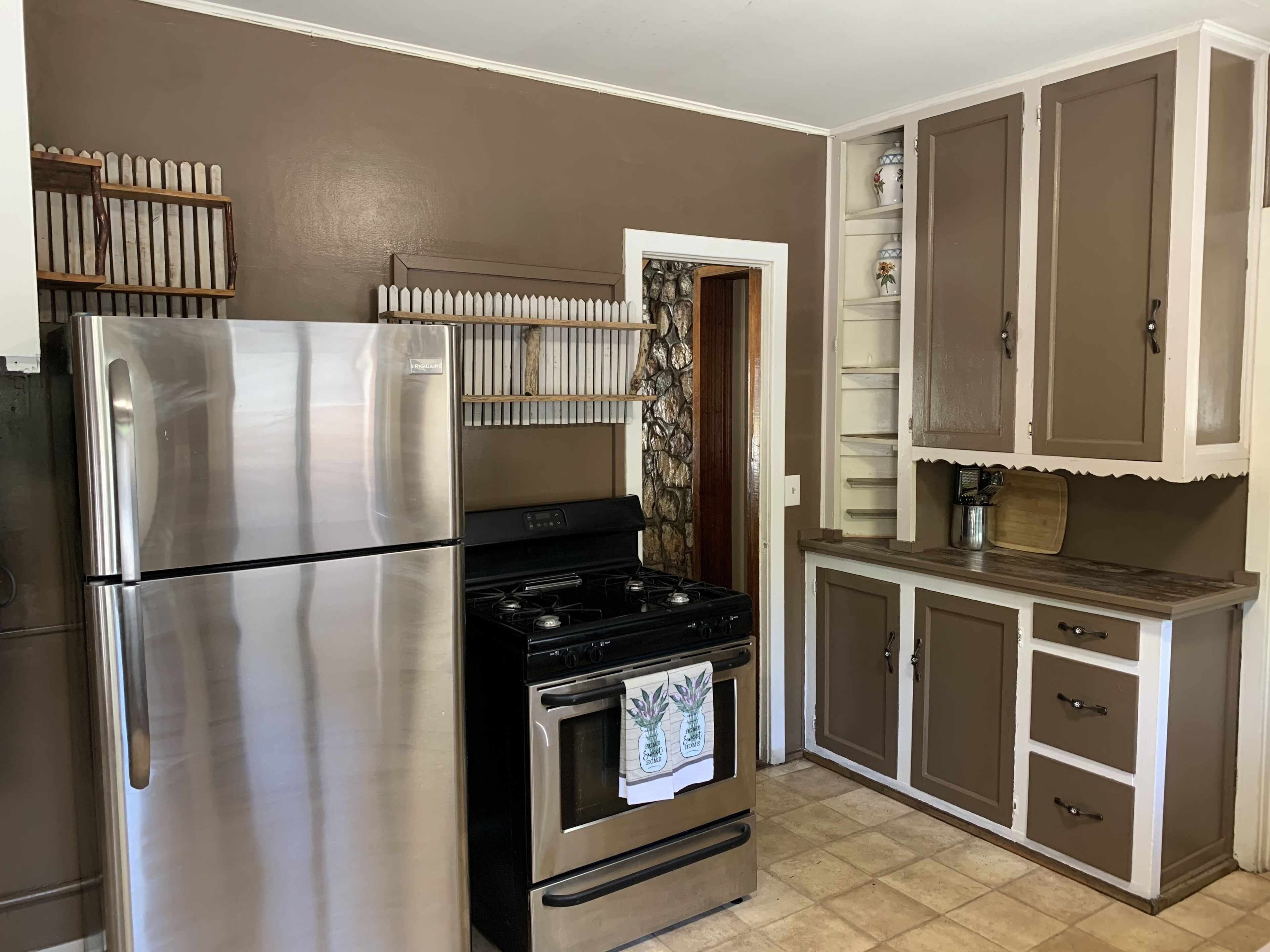 A kitchen with stainless steel appliances, a stove, and wooden cabinets.