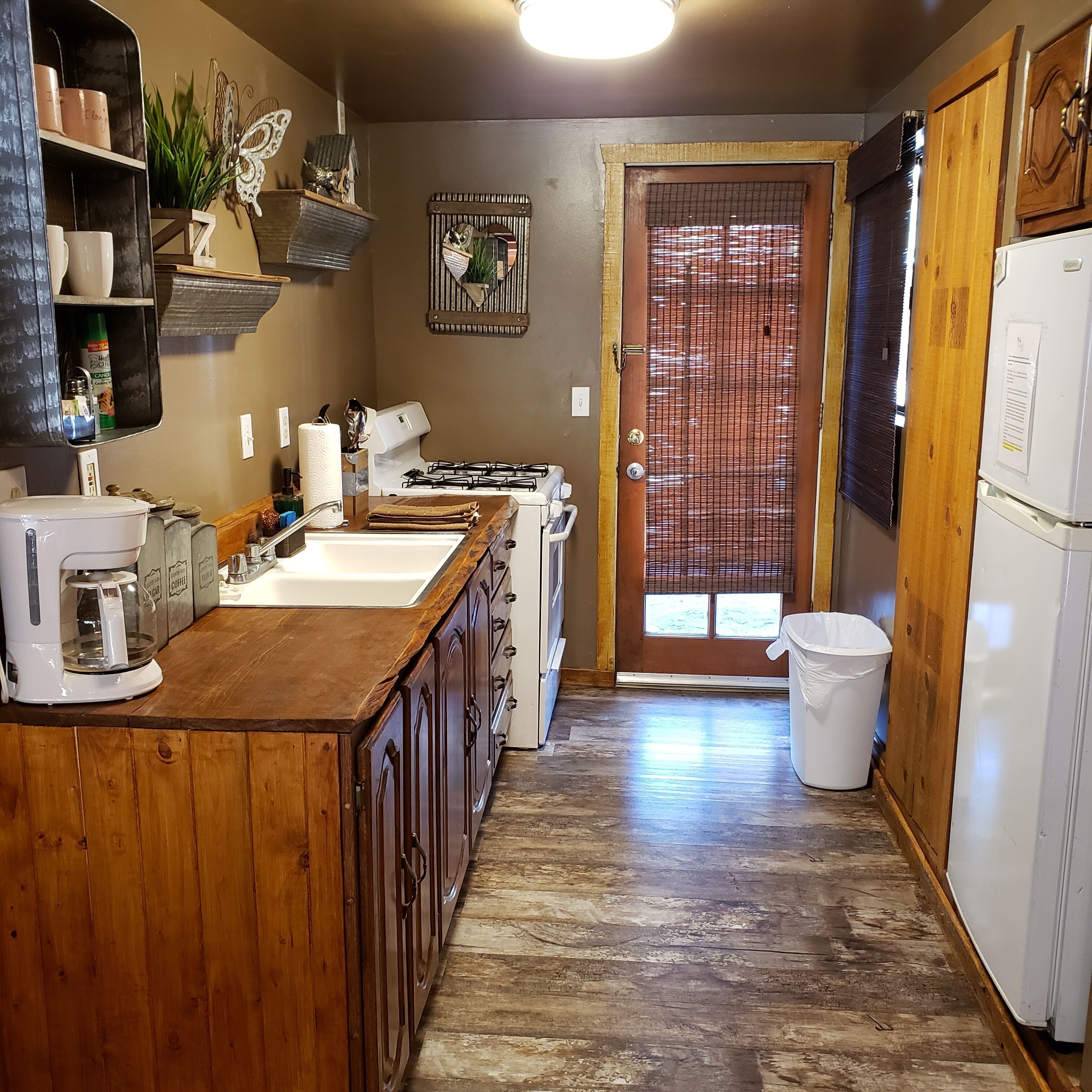Una cocina con armarios de madera, cafetera, lavamanos y refrigerador.
