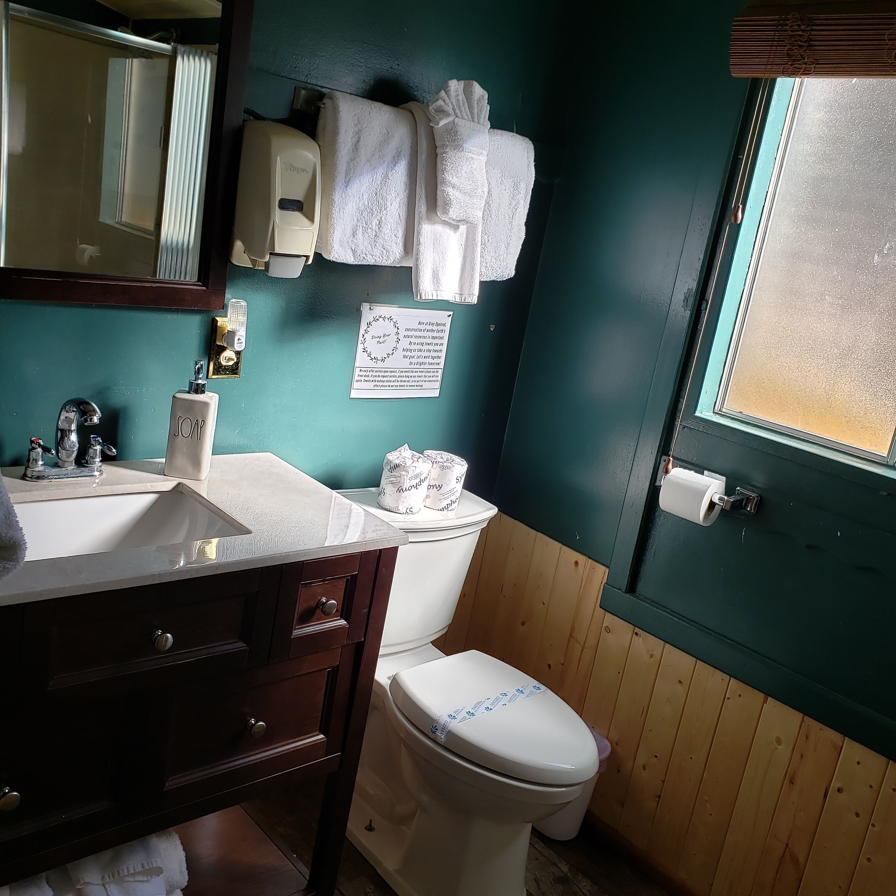 Une salle de bain équipée d’un lavabo, d’un miroir, de toilettes et de serviettes.