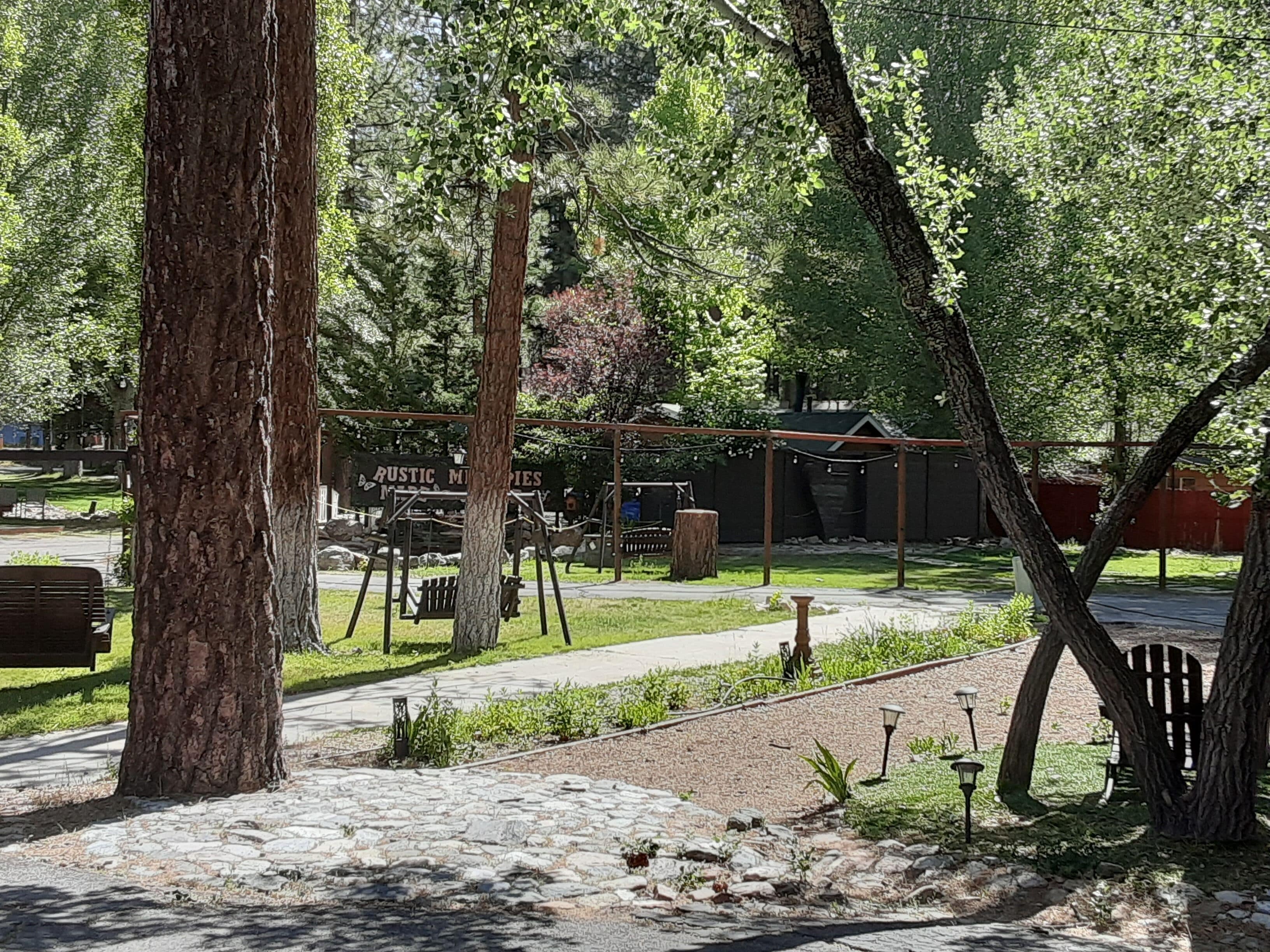 Un parque con un área de juegos, senderos de piedra y árboles.
