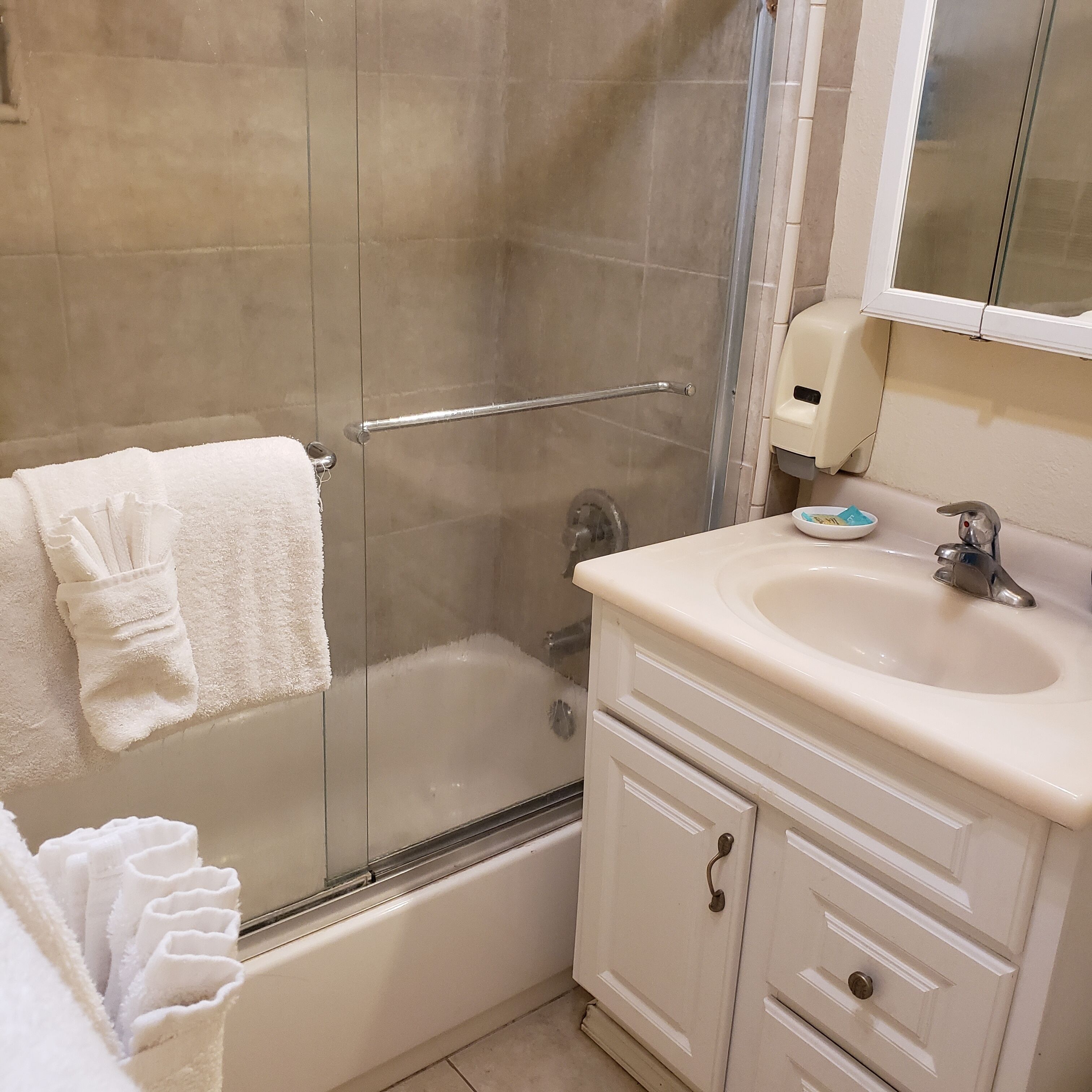 A bathroom with a glass shower enclosure, a bathtub, a sink, and a mirror above the sink.