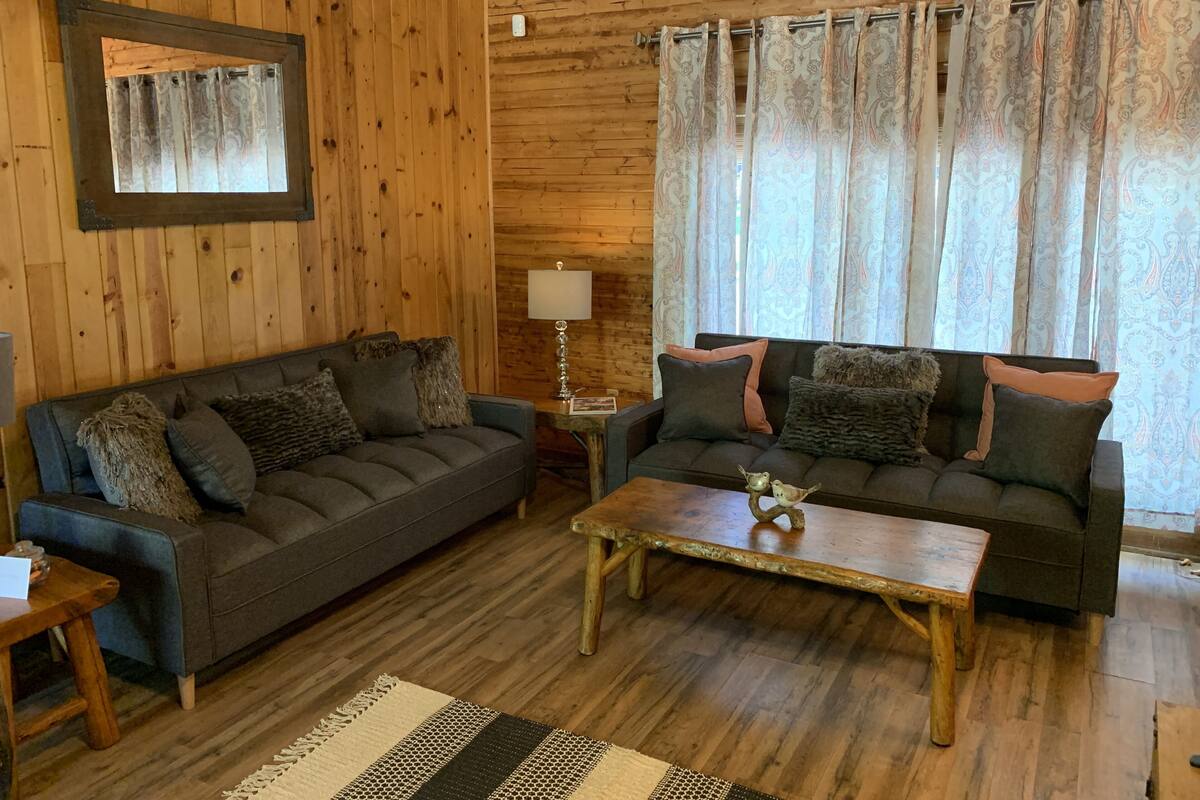 A cozy living room with two sofas, a coffee table, and a wooden floor.