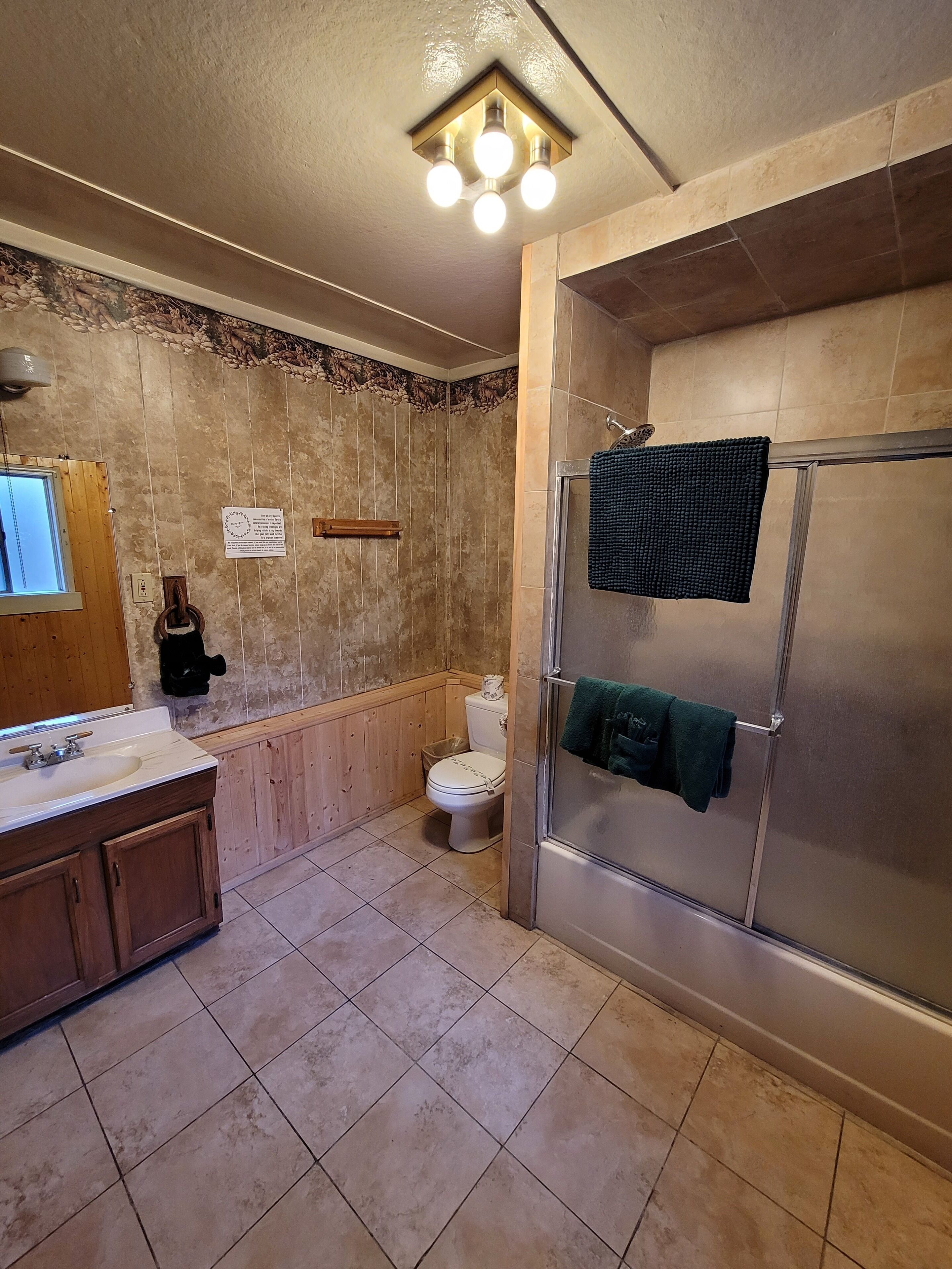 Un bagno con un mobile bagno in legno, un water e un box doccia in vetro.