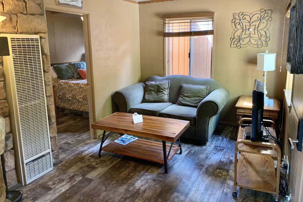 A cozy living room with a stone wall, a couch, a coffee table, and a TV stand.