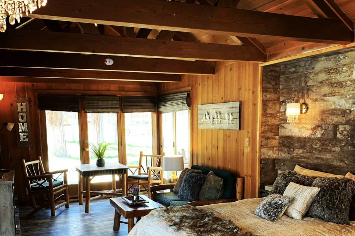 A cozy room with a large bed, wooden walls, and a rustic chandelier.