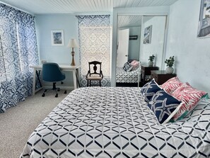 Cozy retreat with a geometric-patterned bedspread, desk, and comfortable seating area.