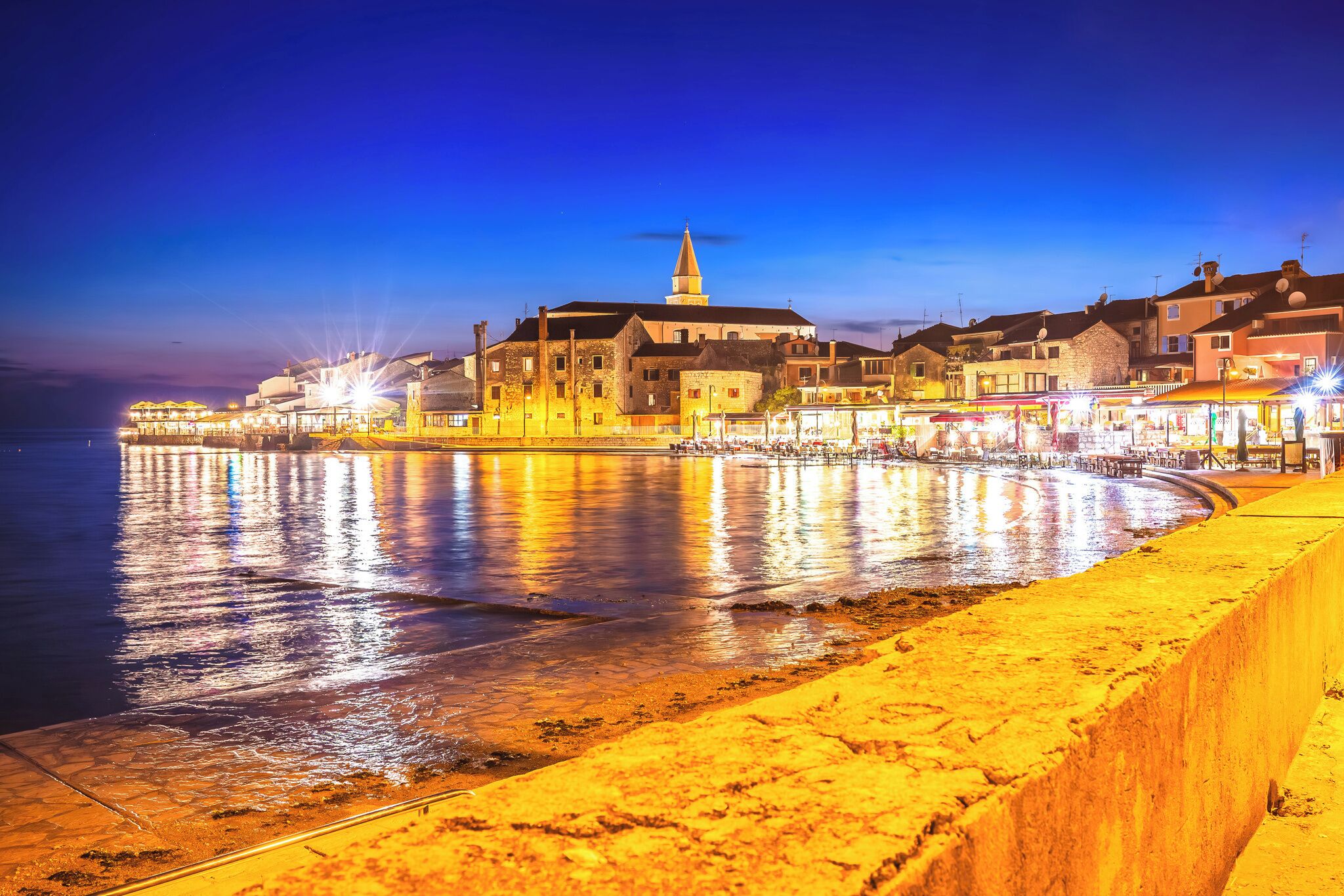 Une promenade en bord de mer bordée d’immeubles, d’une église et d’une jetée.