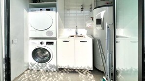 A compact laundry room with a washing machine, dryer, and a small sink.