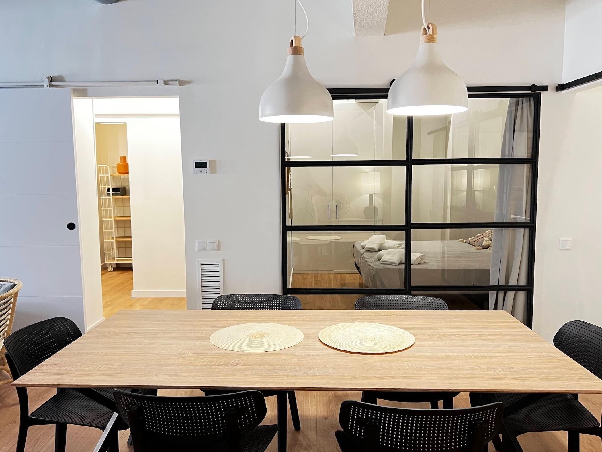 A modern dining area with a wooden table, black chairs, and two pendant lights.