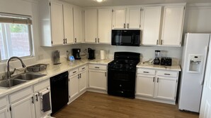 A modern kitchen with white cabinets, a black stove, a microwave, and a dishwasher.